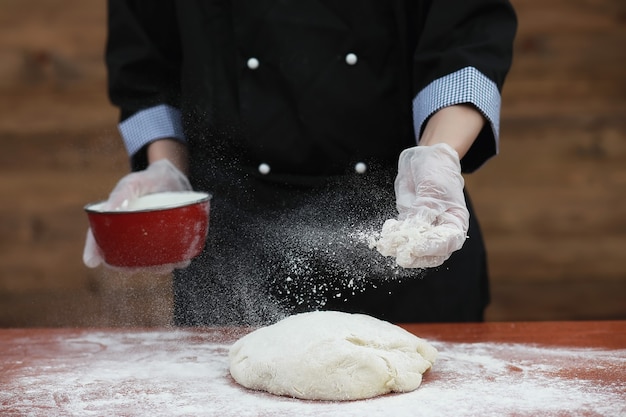 The cook makes flour out of flour for baking on the table