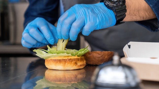 Cuocere preparando hamburger, aggiungendo sottaceti, food truck