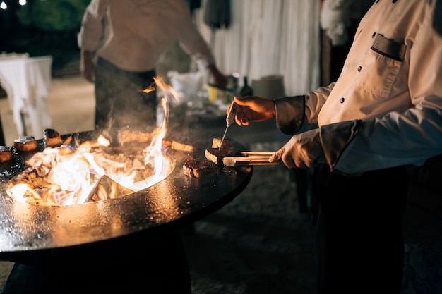 The cook measures the temperature of the steak with a thermometer on the grill