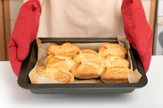 Cook in oven mitt holds baking sheet of scones