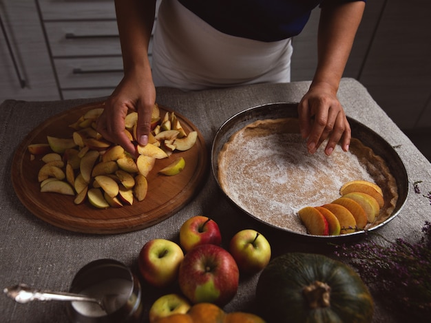 Photo cook places a piece of apple on the surface of the dough