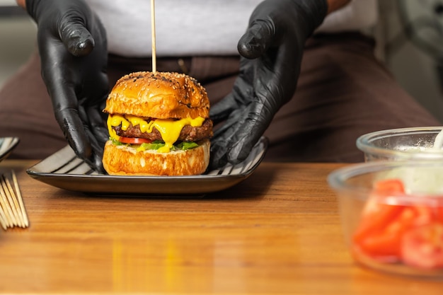 Cook plating a burger in the kitchen of a restaurant