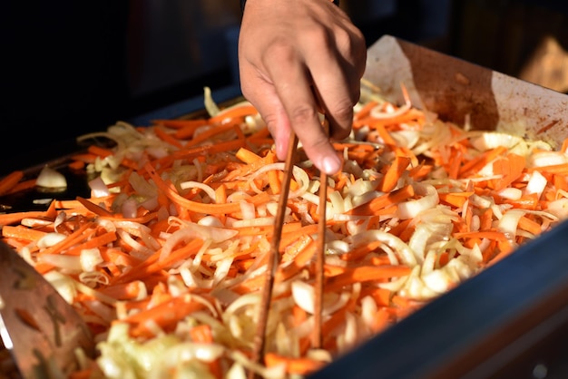 Cook prepares fried fresh vegetables in a wok