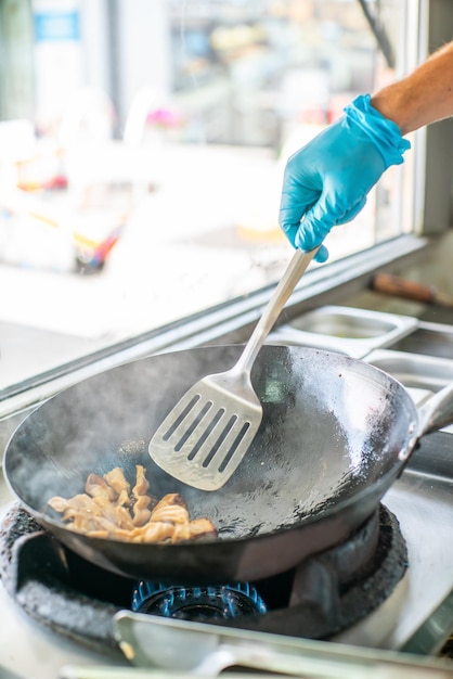 The cook prepares rice noodles for wok Street food