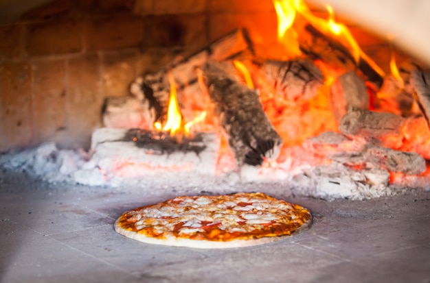 Cook preparing pizza in a restaurant.