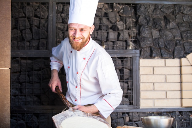 Cook preparing pizza in a restaurant.