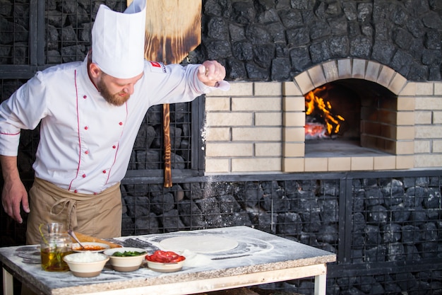 Cook preparing pizza in a restaurant.