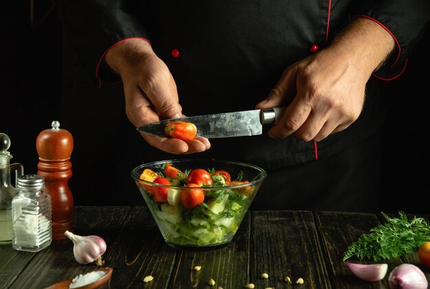 The cook preparing vegetable salad in hotel kitchen Concept of preparing vegetable menu
