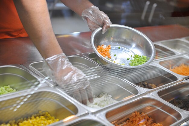 Photo the cook puts pieces of vegetables for salad in a bowl tray with assorted for salad