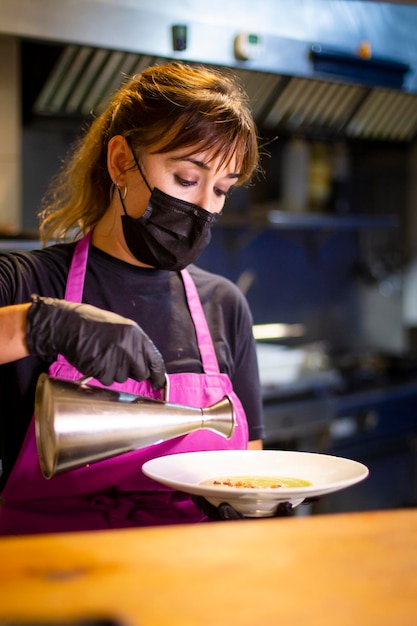 Cook in a restaurant kitchen pouring oil into a dish