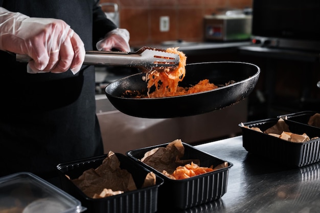 cook roasts carrots in a frying pan in the kitchen in a restaurant