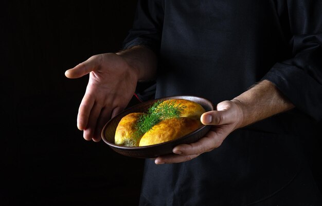 The cook serves baked dill pies in a bowl Free black space for menu or recipe