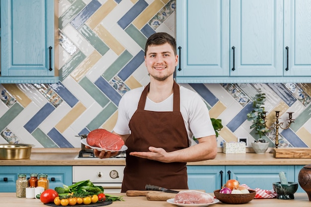 The cook shows fresh meat for cooking on a plate