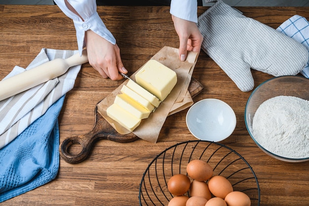 Cook snijdt boter op tafel met ingrediënten.