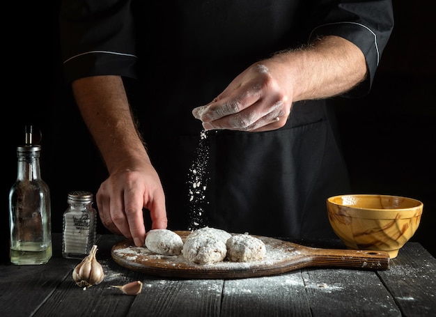 The cook sprinkles flour on cutlets