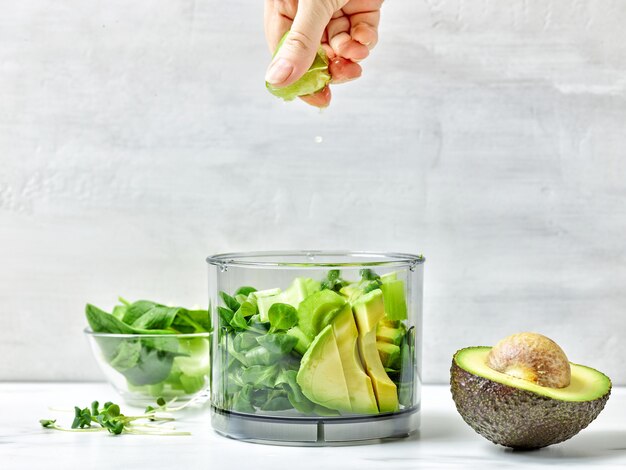 Cook squeezing lime into blender container for making healthy smoothie