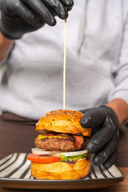 Photo cook sticking a skewer into a readytoeat hamburger