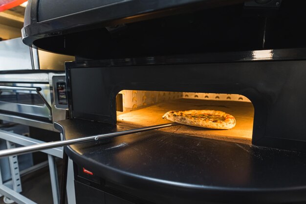 Photo cook taking out baked margarita pizza from oven