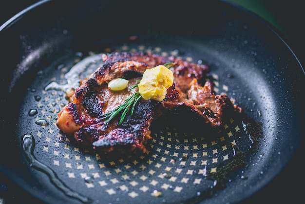 Cooked beef steak with rosemary and garlic inside iron skillet