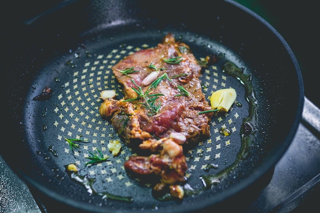 Cooked beef steak with rosemary and garlic inside iron skillet