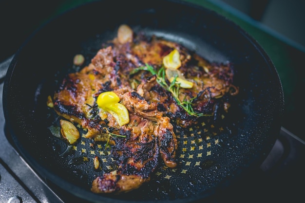 Photo cooked beef steak with rosemary and garlic inside iron skillet