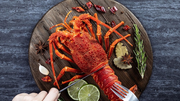 Cooked boiled lobster delicious dinner seafood meal set with\
knife and fork on black stone slate background restaurant menu\
design top view overhead