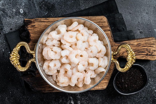 Cooked boiled Peeled Shrimps Prawns in skillet Black background top view