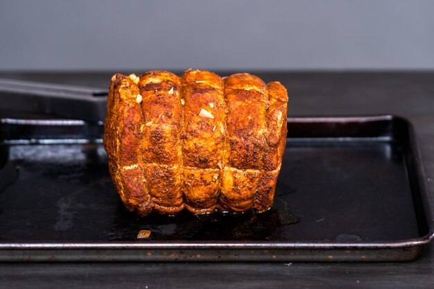 Photo cooked boneless pork roast seasoned with spices on baking sheet.