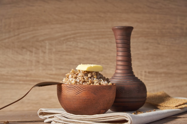 Cooked buckwheat cereal in brown clay bowl on wooden table. gluten free grain for healthy diet