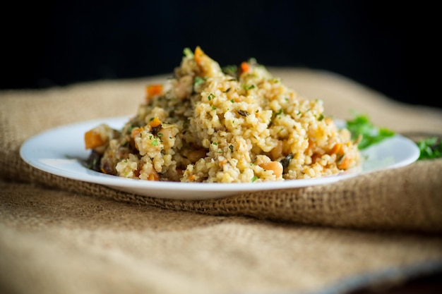 Foto bulgur cotto con carote di verdure e funghi secchi in un piatto