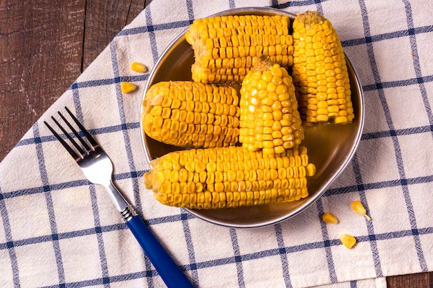 Cooked corn on a plate over old wooden table