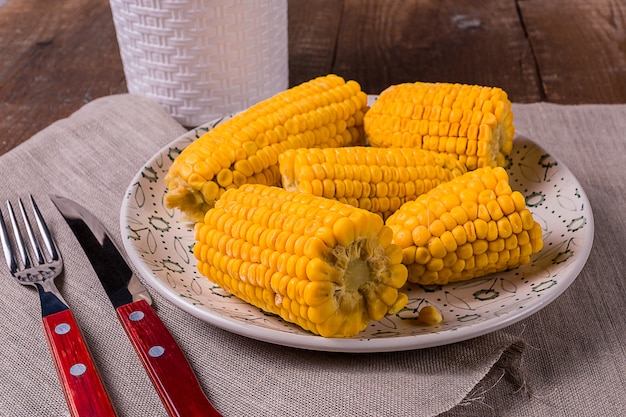 Cooked corn on a plate over old wooden table