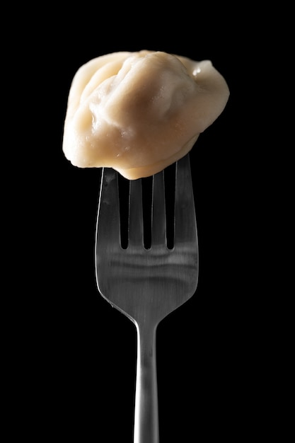 Cooked dumplings on a fork on a black background