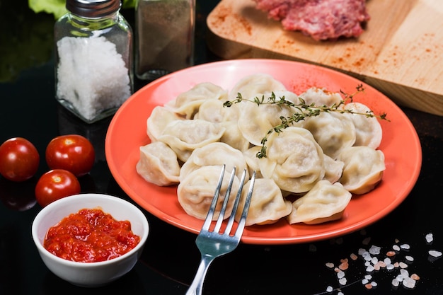 Cooked dumplings on a plate on a black background with ingredients