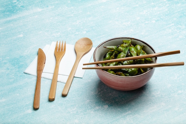 Cooked edamame on a blue tabletop. Snack soybean pods