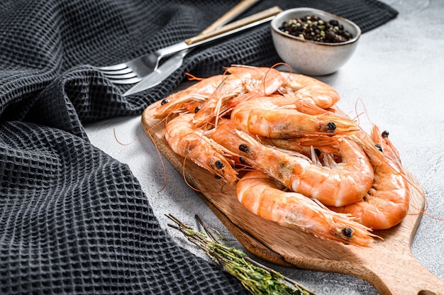 Cooked fresh giant prawns on a wooden chopping Board. White background. 