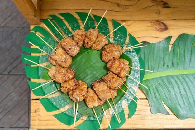 Cooked grilled roasted pork sticks are arranged on the banana leaf  at outside garden