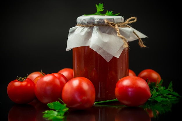 Cooked homemade tomato juice canned in a jar of natural tomatoes isolated on black background