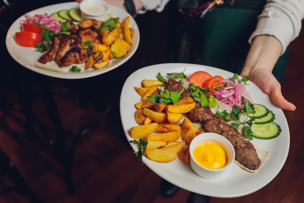 Cooked hot meat with vegetables in a frying pan in the hands of the restaurant waiter