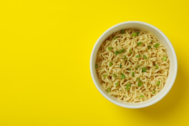 Tagliatelle istanti cotte in bicchiere di carta su giallo