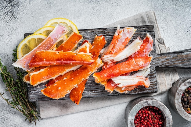 Cooked King Crab legs meat on a wooden board with herbs. White background. Top view.