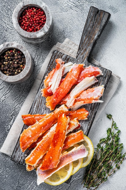 Cooked King Crab legs meat on a wooden board with herbs. White background. Top view.