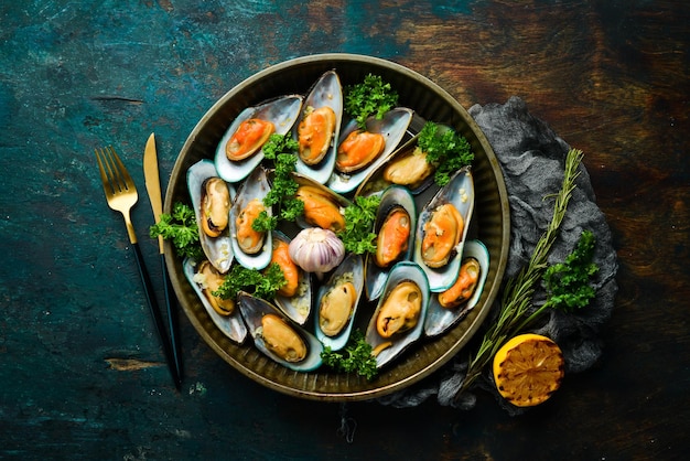 Cooked large green mussels with garlic parsley and lemon on a metal tray Seafood Free space for text