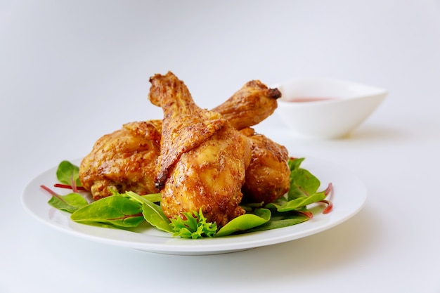 Cooked legs of chicken with spinach on white plate