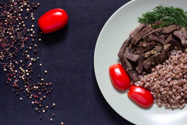 Cooked liver and buckwheat on light green plate on the black background