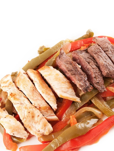 Cooked Meat and chicken with red and green peppers on a white plate