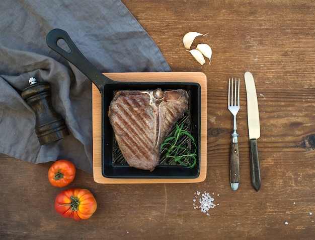 Photo cooked meat steak in small cooking pan over rustic wooden table