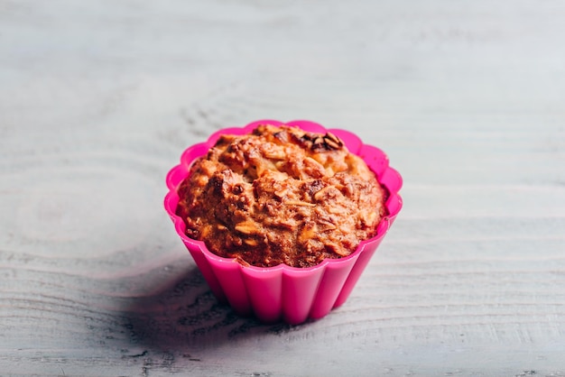 Focaccina di farina d'avena cotta in una teglia in silicone rosa su sfondo di legno chiaro.