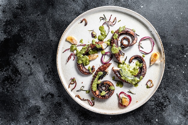 Cooked octopus tentacles with pesto, thyme and onion