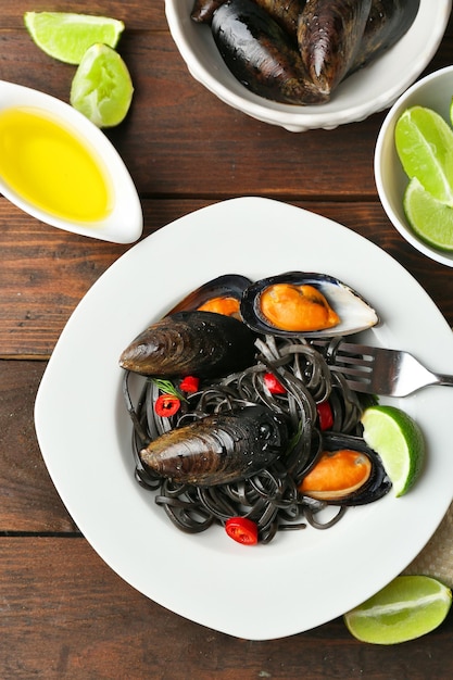 Cooked pasta mussel and lime on brown wooden background